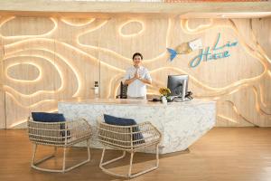 a man standing at a counter in a room with a wall at LIV Hotel Phuket Patong Beachfront in Patong Beach