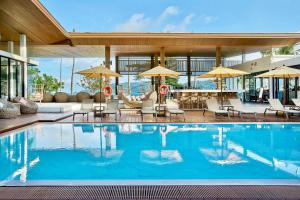 a pool with chairs and umbrellas in a building at LIV Hotel Phuket Patong Beachfront in Patong Beach