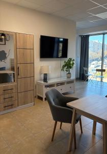 ein Wohnzimmer mit Fernseher, Sofa und Tisch in der Unterkunft Studio Olecko in Olecko