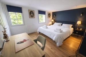 a bedroom with a large white bed and a table at Le Lavoir de Loches in Loches