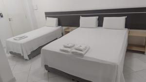 two beds in a hotel room with towels on them at Hotel Minas Brasil in Montes Claros
