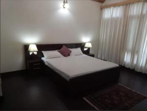 a bedroom with a bed with two lamps and a window at Peaceful huts in Manāli