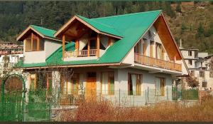 a house with a green roof on top of it at Peaceful huts in Manāli