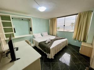 a bedroom with a bed and a desk with a computer at Residencial Morada Coqueiros in Florianópolis
