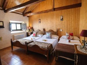 a bedroom with two beds in a room with wooden walls at Medieval country house Señorío de Montero in Cenizate