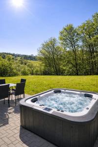 a hot tub in a field with a table and chairs at Ferienhaus Haselnuss in Schleiden