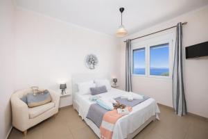 a bedroom with a bed and a chair and a window at Villa Alya View in Barbati