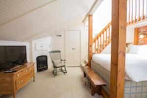 a bedroom with a bed and a desk with a television at The Little Inn in Bayfield