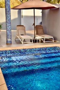 two chairs and an umbrella next to a swimming pool at La belle vie in Rufisque +14 photos