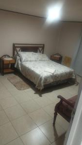 a bedroom with a bed and two night stands and a chair at Depto 4 in Sierra de la Ventana