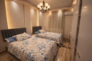 a bedroom with two beds and a chandelier at Cabilyt Cairo Luxiury Apartment in Obour