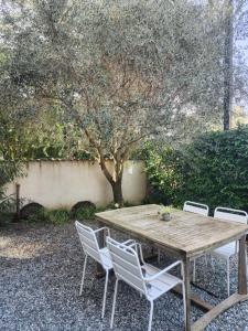 a wooden table with four chairs and a tree at Chaleureux appartement in Nîmes