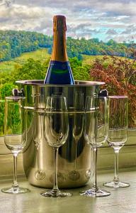 a bottle of wine in a bucket with four wine glasses at Ranmore Rise Retreat in the Surrey Hills in Dorking