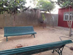 a green bench in front of a red building at KEUR MAMY DOUSSOU à Ndangane campement in Ndangane