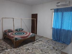 a bedroom with a bed and a blue curtain at KEUR MAMY DOUSSOU à Ndangane campement in Ndangane