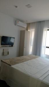 a bedroom with a large bed and a flat screen tv at Flat colado a praia de Boa Viagem in Recife +3 photos