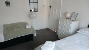 a bedroom with two beds and a dresser and a mirror at Zoran home 3 in Leicester +1 photo