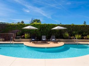 two chairs and umbrellas next to a swimming pool at Walnut Creek Marriott in Walnut Creek