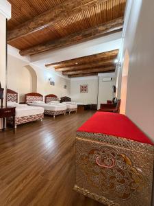 a large room with two beds and a red rug at SHoxtut INN 18-19Th Century in Bukhara