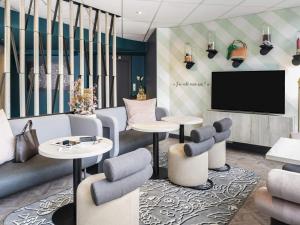 a lobby with tables and chairs and a flat screen tv at ibis Styles Sceaux Paris Sud in Sceaux