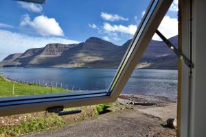 a view of a lake from a window at FjordNest Cabin in Hvannasund