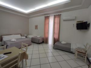 a room with two beds and a table and a tv at Angolo Lamia Sicily Apartment in Partinico