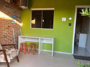 a green wall with a table and two stools at Refúgio do Bosque in Penha