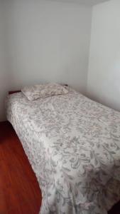 a bed with a white comforter on top of it at Habitación Privada Centro in Ayacucho
