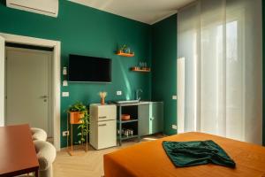 a green room with a bed and a television on a wall at MR Suites Bergamo in Seriate