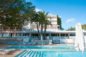 a pool at a hotel with chairs and a umbrella at Hotel Na Taconera Sport & Relax in Cala Ratjada