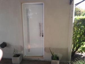 a white door on a white wall with plants at Depto in Navarro
