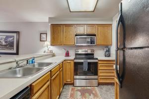 a kitchen with wooden cabinets and a stainless steel refrigerator at Golf Course Retreat - Pool Access Lake Views in McCall