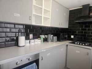a kitchen with white cabinets and black brick walls at Seraphic Homes Medway Kent in Gillingham +22 photos