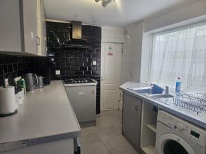 a kitchen with a sink and a washing machine at Seraphic Homes Medway Kent in Gillingham