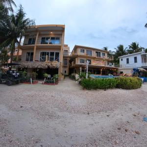 a large building on the beach next to a resort at Beach Club Budget Rooms at Popeyes Caye Caulker in Caye Caulker