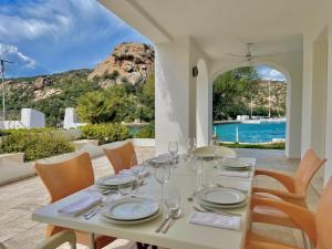 a white table with wine glasses and a view of the water at Poltu Quatu House in Porto Cervo