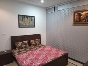 a bedroom with a bed with a red bedspread at The Velmora G-13 in Islamabad