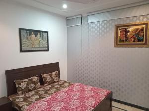 a bedroom with a bed and two pictures on the wall at The Velmora G-13 in Islamabad