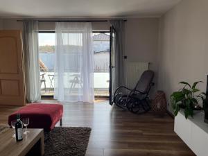 ein Wohnzimmer mit einem Sessel und ein Zimmer mit Balkon in der Unterkunft Ferienwohnung Eich in Kelberg