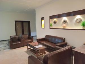 a living room with leather couches and a table at The Norvane G-13 in Islamabad