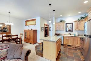 a kitchen with wooden cabinets and a living room at McCall Golf Condo - Pool Courts & Patio in McCall