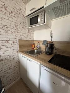 a kitchen with a sink and a microwave at Studio cosy in Valenciennes