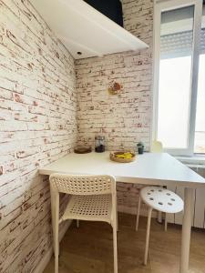 a white table and chairs in a room with a brick wall at Studio cosy in Valenciennes