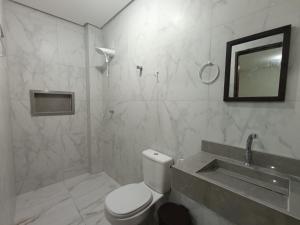 ein Badezimmer mit Toilette, Waschbecken und Spiegel in der Unterkunft Pousada Paulo's in Caruaru