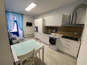eine Küche mit weißen Schränken, einem Tisch und Stühlen in der Unterkunft Casa Mareo in Capraia