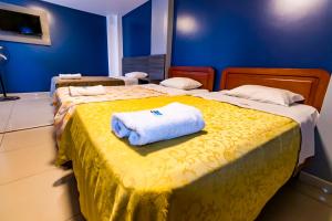 zwei Betten in einem blauen Zimmer mit Handtüchern darauf in der Unterkunft Hotel JORGE CHAVEZ in Trujillo