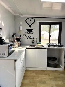a kitchen with white cabinets and a coffee sign on the wall at Casa Bonassola, Barra de Navidad in Barra de Navidad
