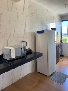 a kitchen with a counter with a microwave and a refrigerator at Casa Portal Carrancas in Carrancas