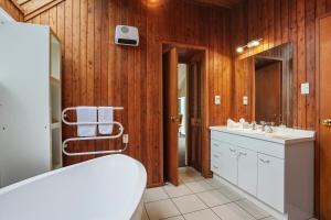 a bathroom with a tub and a sink and a mirror at Waitati Retreat in Waitati +20 photos