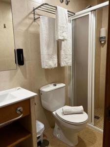 a bathroom with a toilet and a shower and towels at Hostal Costabella in Fuengirola +47 photos